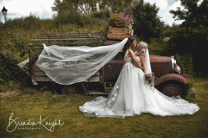 bride and bride kissing next to a rusty 1920's truck covered in flowers
