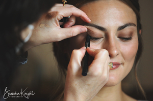 makeup artist applying eye makeup to bride