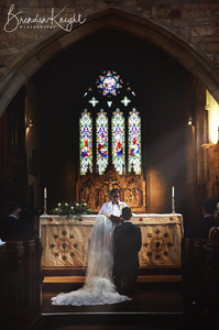 bride and groom Kneeling in church bathed in sunlight 