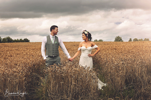 bride and groom holding hands in a wheat field