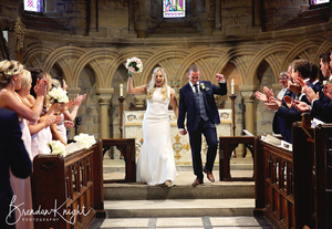 Bride and groom celebrating as they walk down the aisle in church